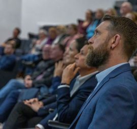 An audience at a research conference, a sideshot in the stands.