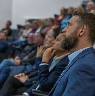 An audience at a research conference, a sideshot in the stands.